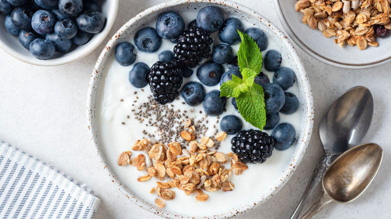 A bowl of yogurt with berries and granola next to ingredients