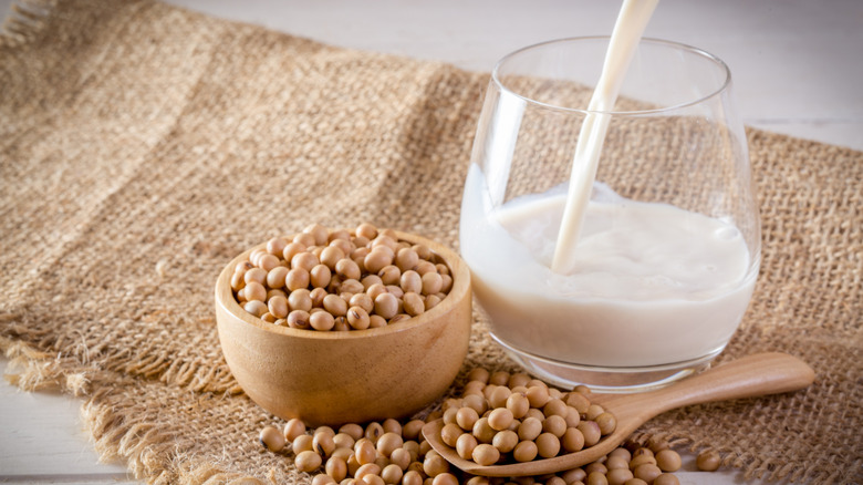 dried soy beans next to soy milk being poured into a glass