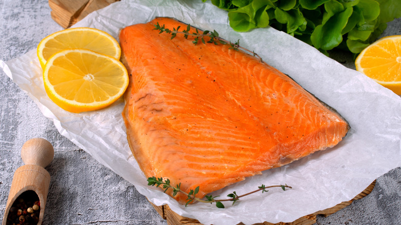 smoked rainbow trout on a white parchment paper with lemons and herbs