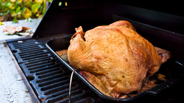 A turkey in a roasting pan on a grill