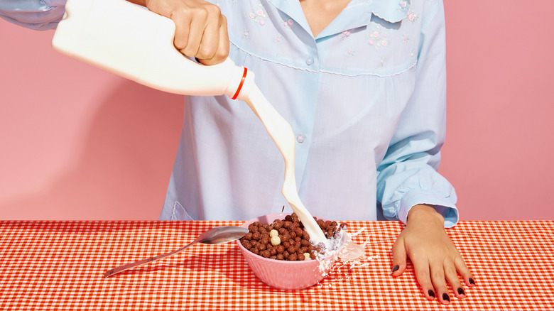 A retro style image of a woman pouring milk into a bowl of chocolate puff breakfast cereal