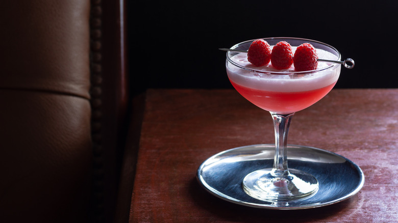 Clover Club Cocktail, a Sour Drink with Gin, Raspberries, and Egg White Foam in a Dark Luxurious Bar