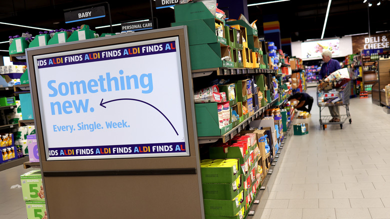 A customer approaches the front entrance of an Aldi Grocery store on a bright sunny day