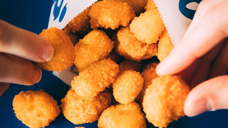 Hands holding Culver's cheese curds spilling out of package