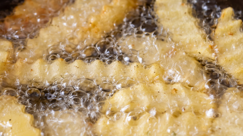 Crinkle-cut fries frying in hot oil