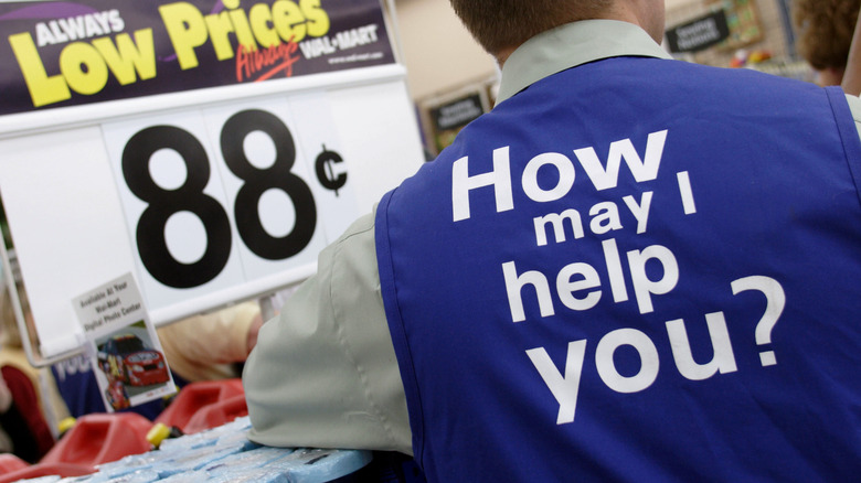 Walmart employee with back of vest that asks "How may I help you?"
