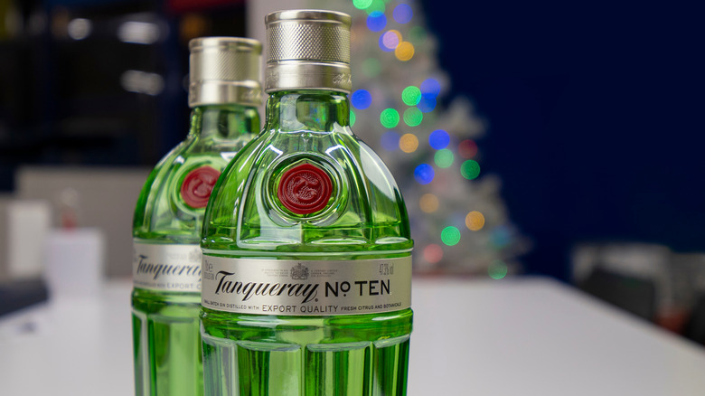Close up of two bottles of Tanqueray No. 10 with blurry christmas lights in background.