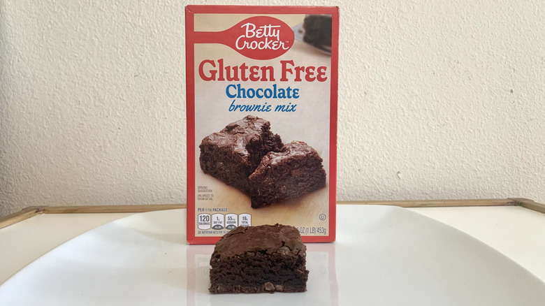 Betty Crocker Gluten Free Chocolate Brownie Mix box alonside a baked brownie