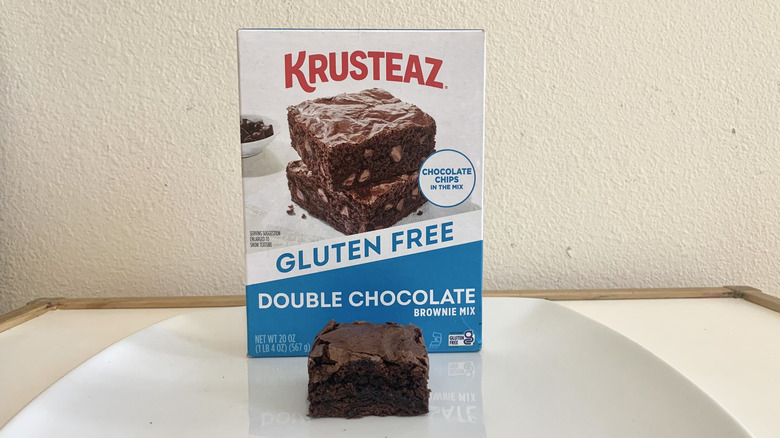 Krusteaz Gluten Free Double Chocolate Brownie Mix box alonside a baked brownie
