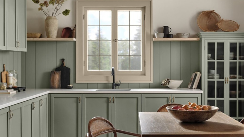 Muted green kitchen with neutral tones and wooden accents