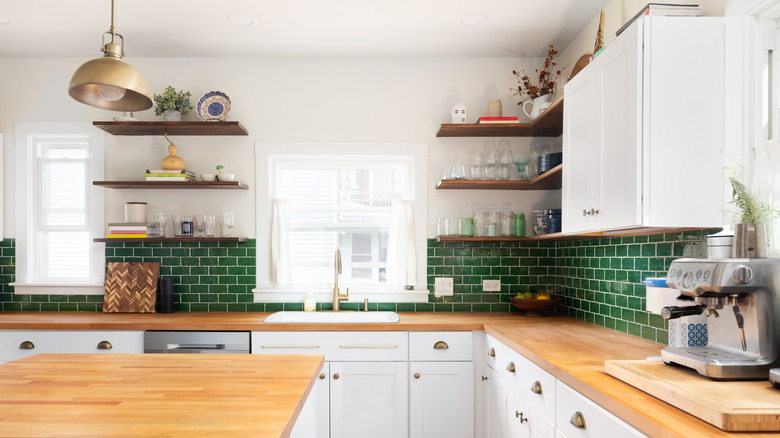 White kitchen with bright window, wooden counters, green tile backsplash