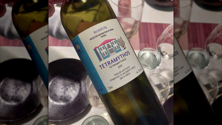 close up of Roditis greek white wine bottle with dinner table in the background