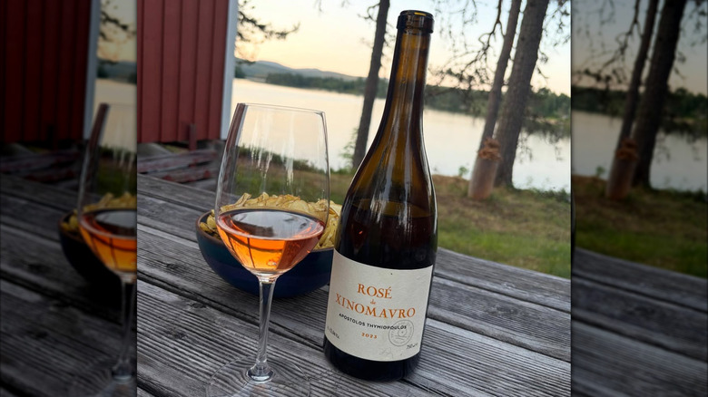 bottle and glass of greek Xinomavro rosé wine with nature scenery in the back