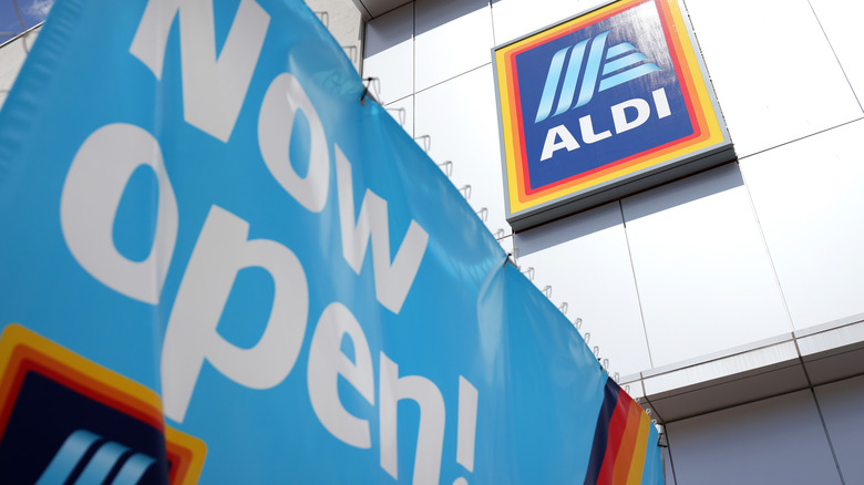 Exterior of Aldi store with Now Open banner in foreground