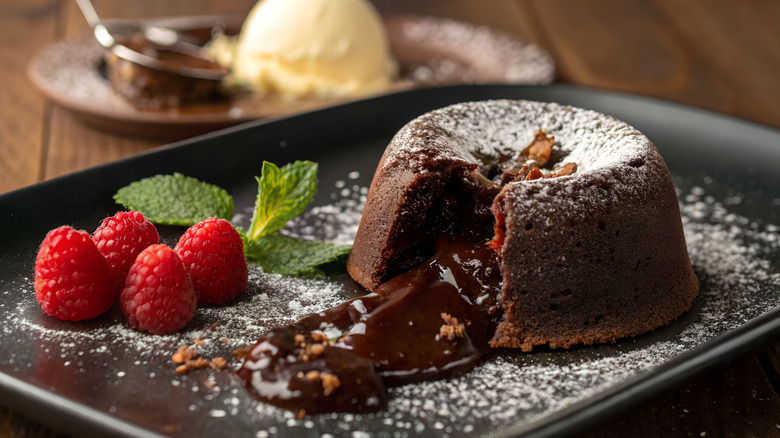 Chocolate lava cake and rasberries on a black plate