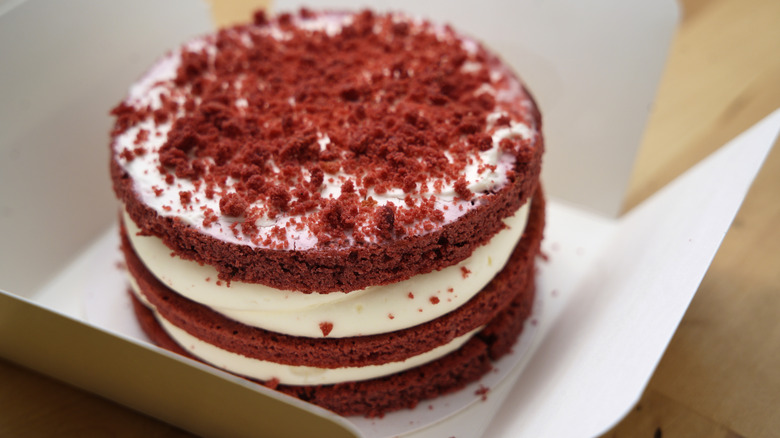 A whole red velevt cake in a cake box