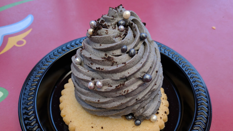 Swirl of grey frosting piped onto cookie, decorated with sugar pearls