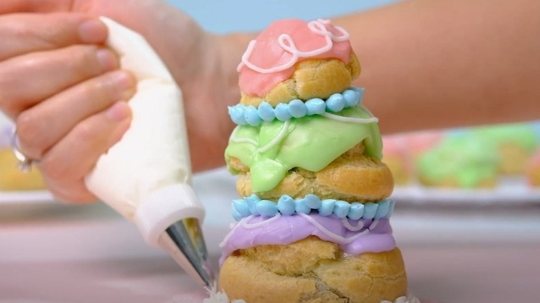 Piping frosting around base of courtesan au chocolat pastry stack
