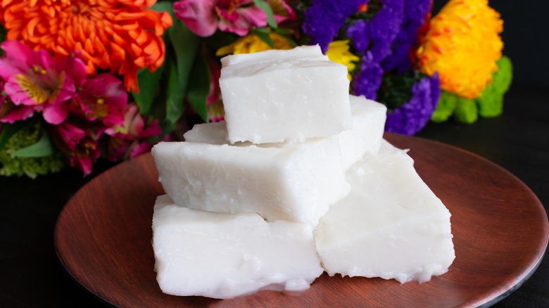 Hands holding broken pieces of Hawaiian haupia coconut pudding