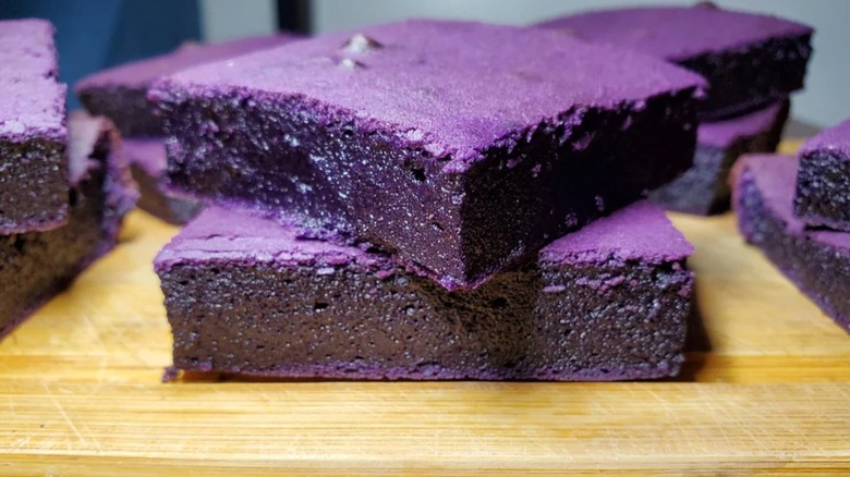 Scooping out slice of ube butter mochi from dish