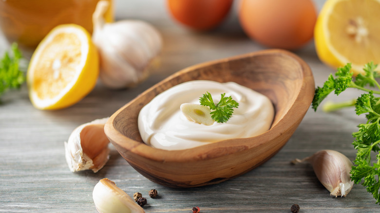 Garlic aioli sauce in bowl surrounded by ingredients on the table