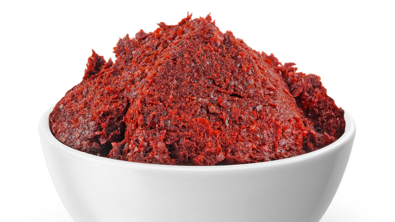 A white bowl filled with spicy red pepper paste (biber salcasi) against a white background