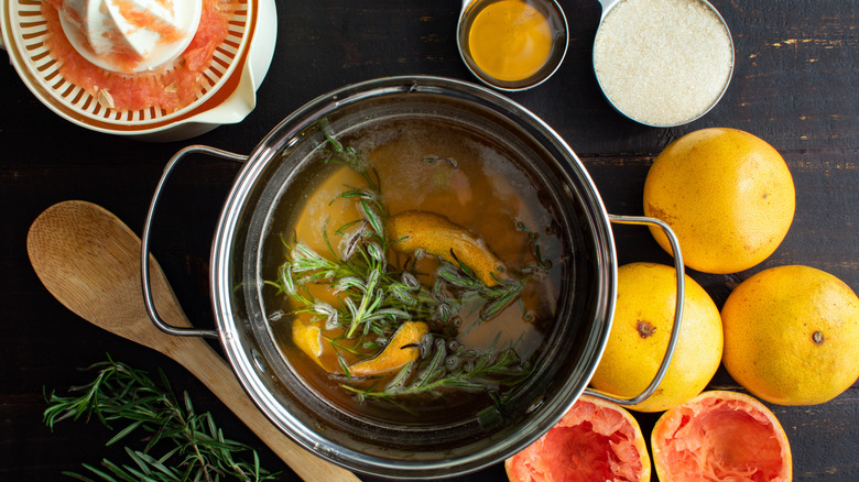 Making Rosemary-Grapefruit Simple Syrup in a Saucepan: Infused simple syrup surrounded by red grapefruit and other ingredients.