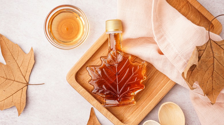 Bottle of maple syrup surrounded by maple leaves