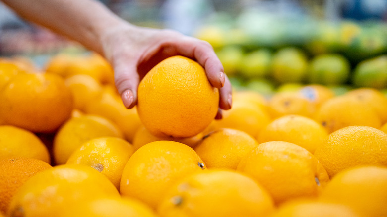 Woman holding whole oranges in the grocery store