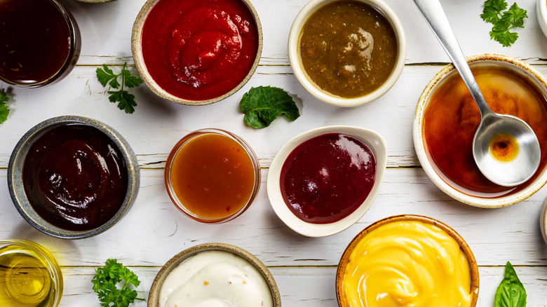 Various sauces in small bowls with herbs in between