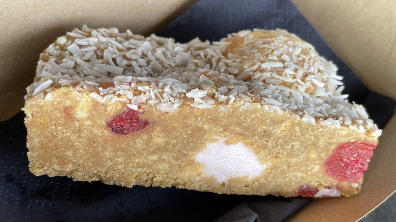 Close up of Fifteens slice showing marshmallows and cherries inside, with coconut on top
