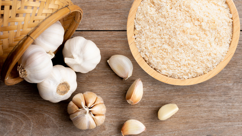 a bowl of granulated garlic and fresh garlic bulbs