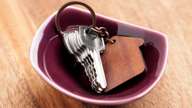 Set of keys placed in ceramic bowl on wooden table