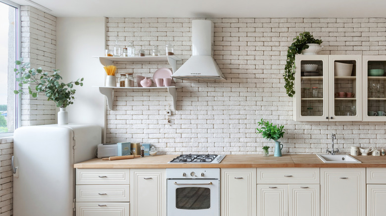 Modern kitchen facade with white shelves above a gas stove