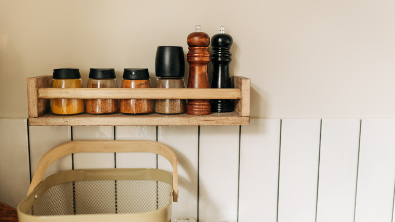 Several spice bottles placed on a wooden shelf