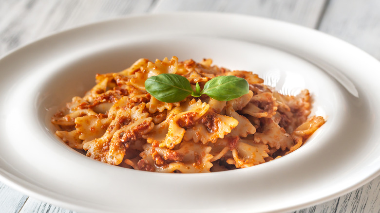 Bowl of farfelle pasta with red pesto and fresh basil