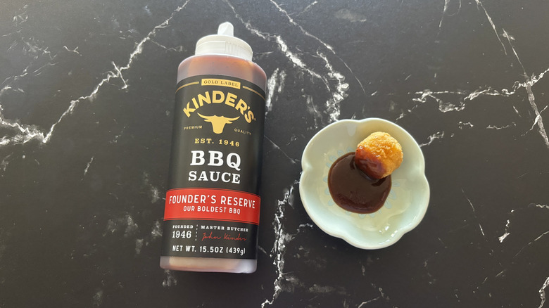 Kinder's Founder's reserve BBQ sauce bottle next to chicken nugget and sauce on plate