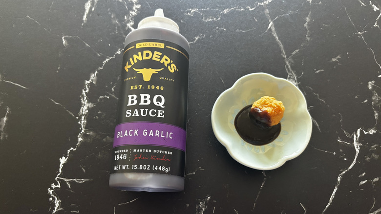 Kinder's black garlic BBQ sauce bottle next to chicken nugget and sauce on plate