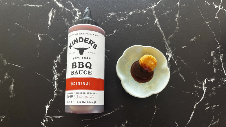 Kinder's original BBQ sauce bottle next to chicken nugget and sauce on plate