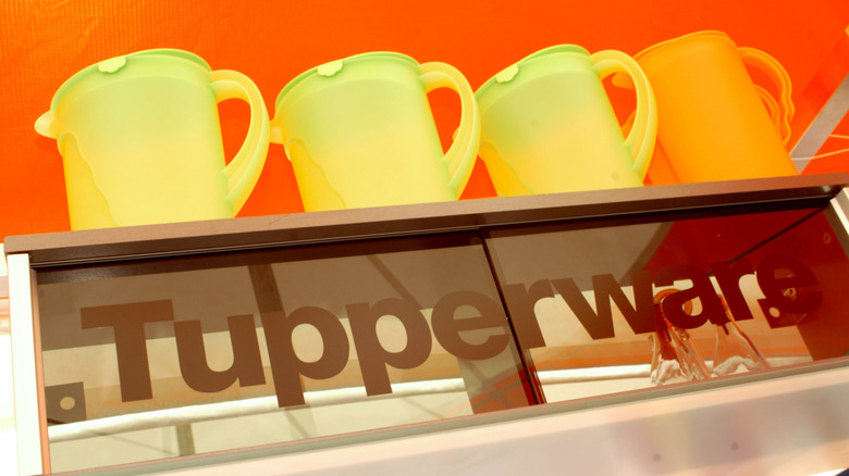 Four Tupperware pitchers stacked atop surface emblazoned with logo