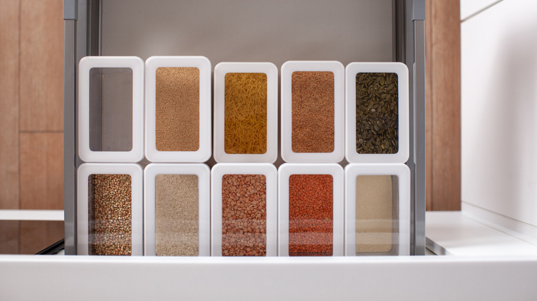Top view of neatly organized grains inside plastic containers stacked in a kitchen pantry