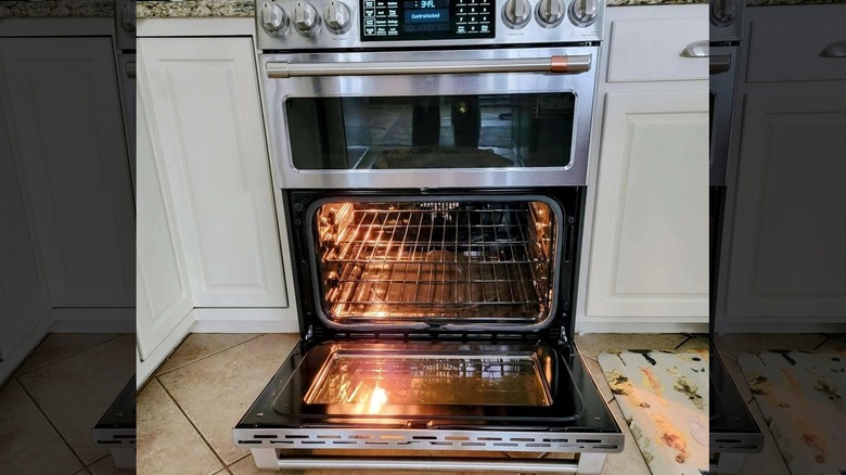 An oven with an open door placed at floor level against white cabinets