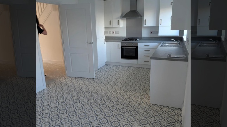 A spacious kitchen featuring gray countertops and white cabinetry