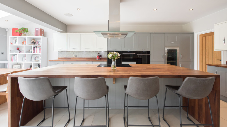 Large wooden kitchen island with 4 grey chairs
