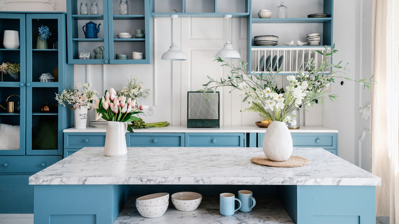 Blue kitchen island with two vases placed on the marble countertop