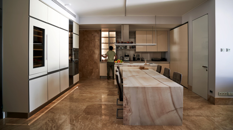 Large kitchen with central island, dining table and a man standing in the distance