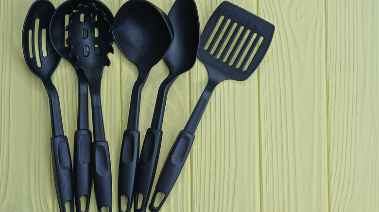 Set of six black plastic spatulas on a wooden table