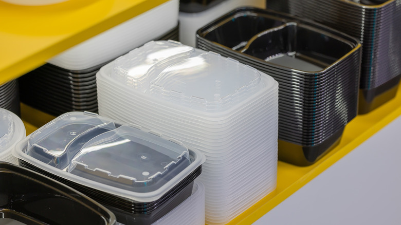 Black plastic containers and lids stacked neatly on a shelf