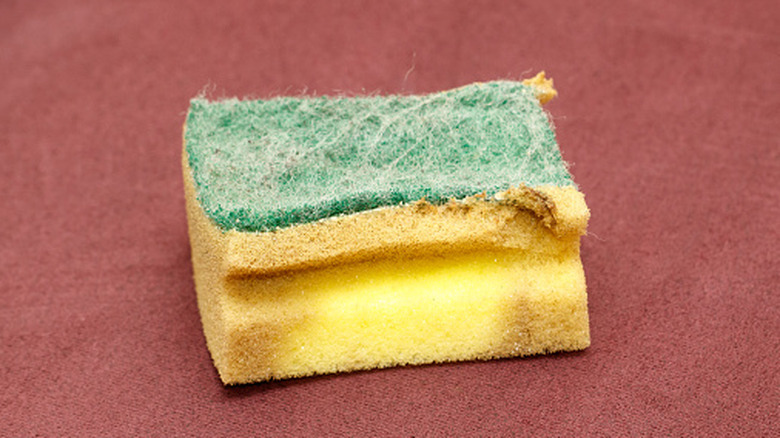 Worn-out kitchen sponge with stains on a table
