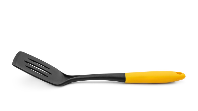 Black plastic spatula isolated against a white background